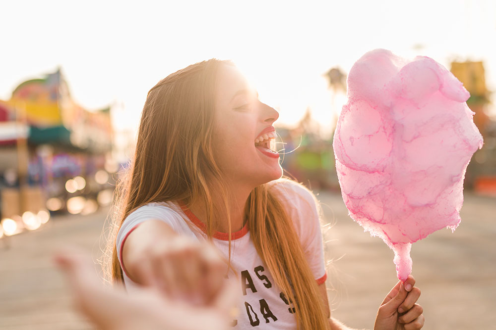 The lady is happy while eating cotton candy