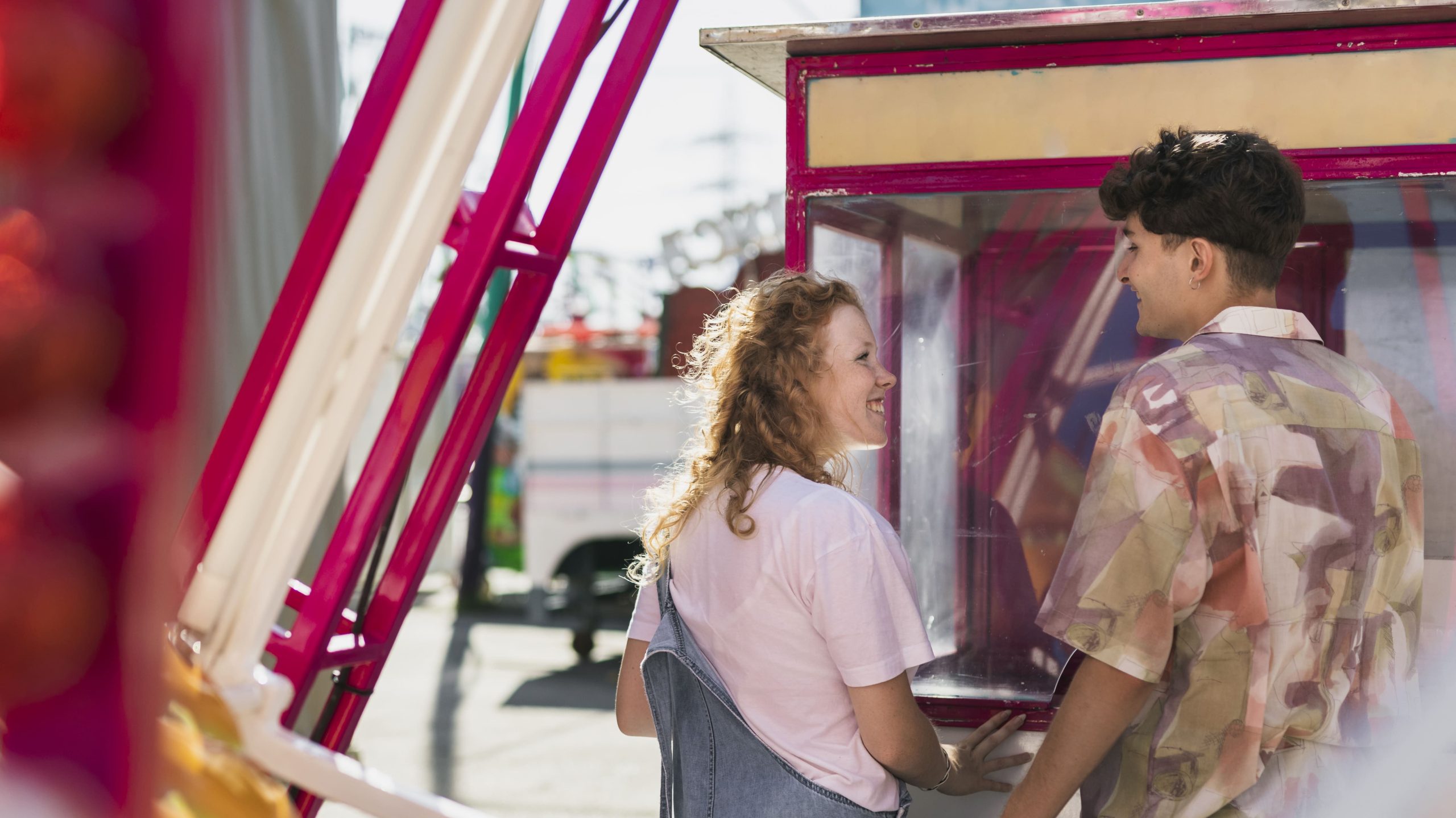 Couple smiling in front of a commercial candy floss machine at an amusement park